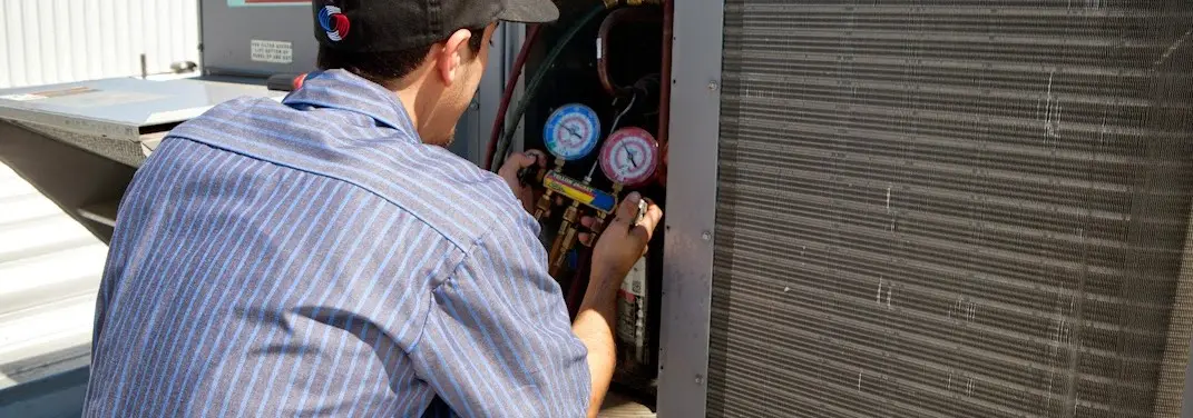 HVAC technician servicing a condenser unit in Mission